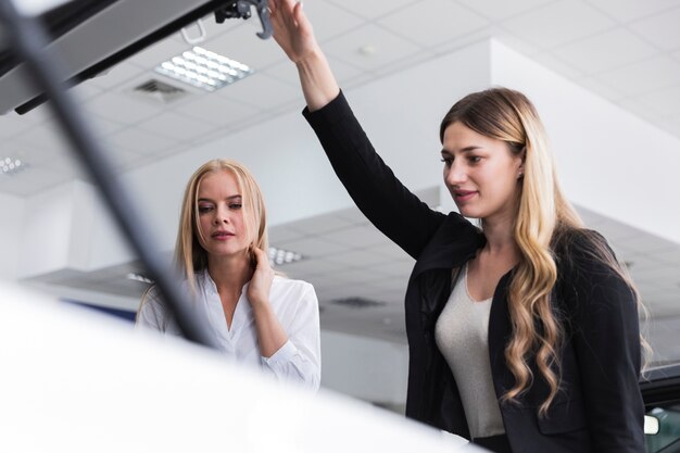 Vista de ángulo bajo de dos mujeres mirando el motor del automóvil