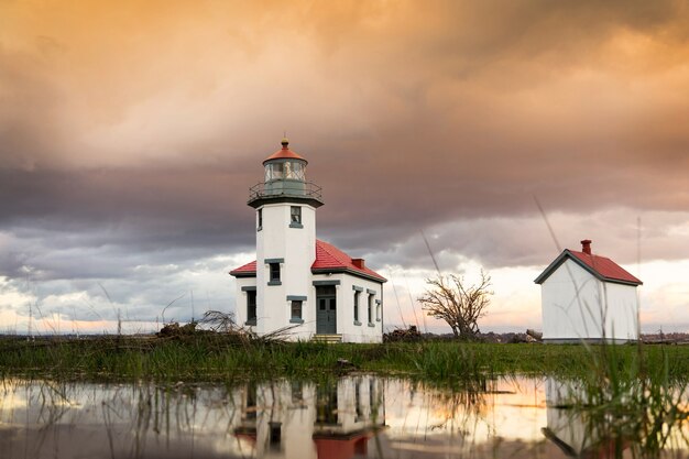 Vista de ángulo bajo los faros en la isla de Vashon bajo un cielo nublado durante la puesta de sol en los EE.