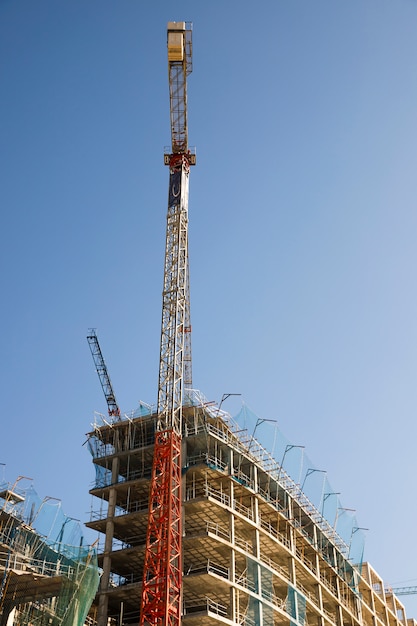 Vista de ángulo bajo de la grúa de construcción cerca del sitio contra el cielo azul