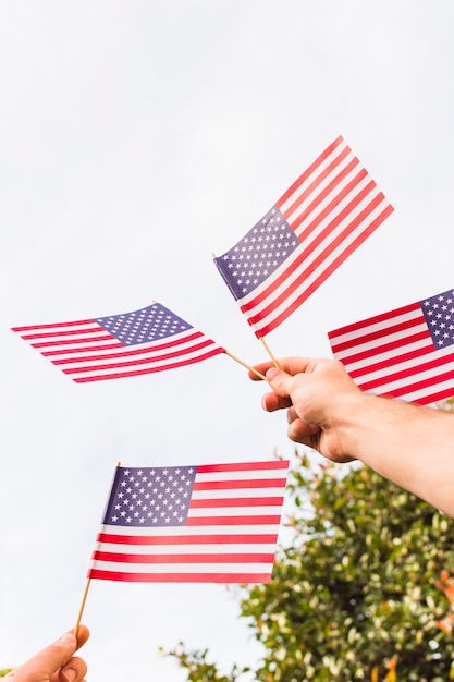 Vista de ángulo bajo de la mano de un hombre sosteniendo banderas de Estados Unidos