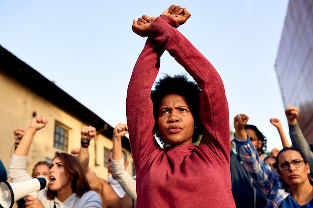 Vista de ángulo bajo de la mujer afroamericana con gesto cruzado de brazos participando en una protesta por los derechos humanos