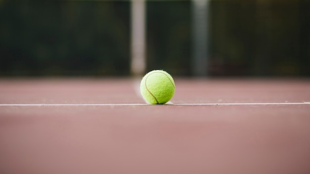 Vista de ángulo bajo con pelota de tenis en campo