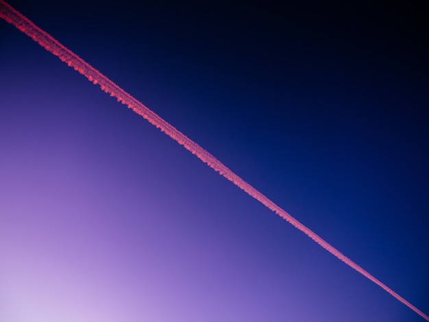 Vista de ángulo bajo de la pista de un avión en un cielo azul durante la noche - ideal para fondos