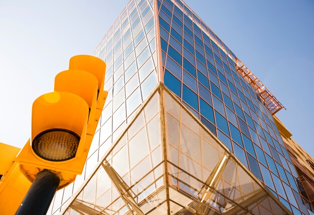 Vista de ángulo bajo del semáforo cerca del moderno edificio corporativo contra el cielo azul