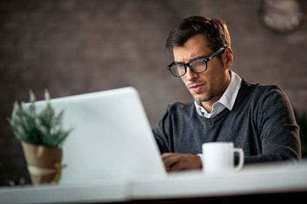 Vista de ángulo bajo del trabajador independiente que usa una computadora portátil y escribe y envía un correo electrónico mientras está en el trabajo