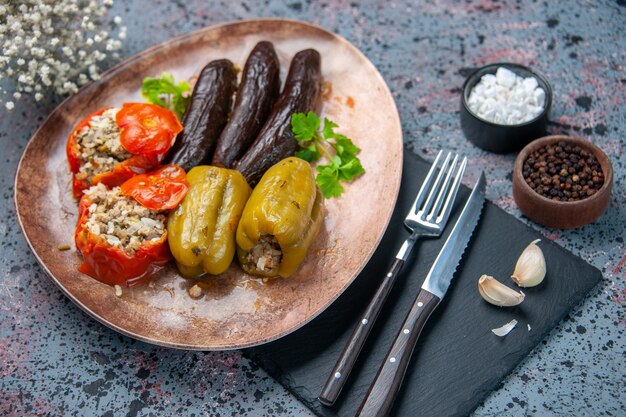 Vista anterior deliciosa comida de dolma vegetal rellena con carne molida sobre fondo azul.