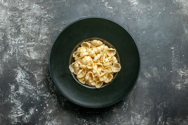 Vista anterior de la deliciosa conchiglie sobre una placa negra sobre fondo gris