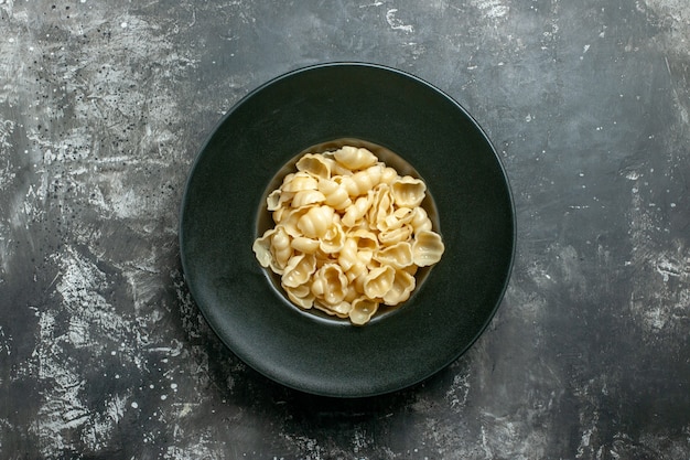 Vista anterior de la deliciosa conchiglie sobre una placa negra sobre fondo gris