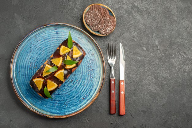 Vista anterior de una deliciosa tarta decorada de naranja con chocolate y galletas en el cuadro negro