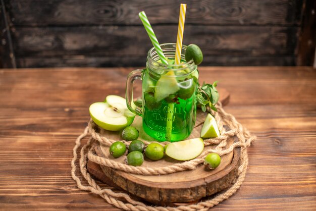 Vista anterior de delicioso jugo de fruta fresca servida con manzana y feijoas sobre una tabla de cortar de madera