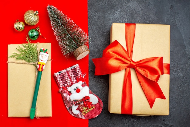 Vista anterior del estado de ánimo navideño con accesorios de decoración de árbol de navidad calcetín de regalo sobre fondo rojo y negro