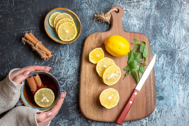 Vista anterior de limones frescos y cuchillo de menta sobre una tabla de cortar de madera