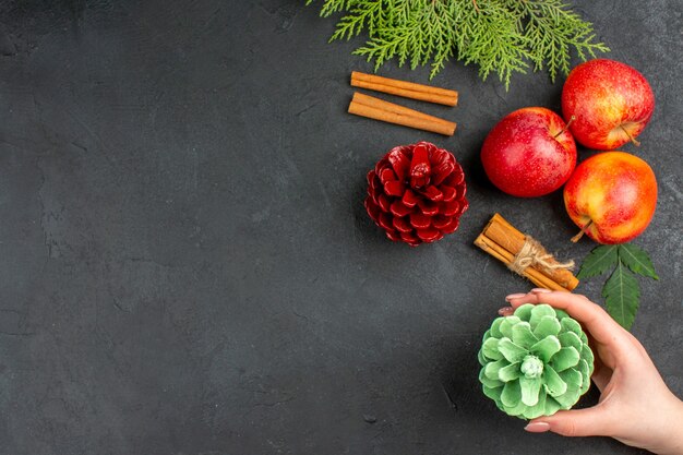 Vista anterior de manzanas frescas, canela, limones y accesorios de decoración sobre fondo negro