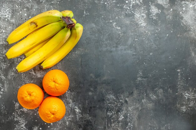 Vista anterior de naranjas frescas y paquete de banano orgánico natural en el lado derecho fondo oscuro