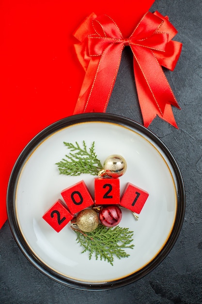 Foto gratuita vista anterior de los números de accesorios de decoración en un plato y una cinta roja sobre una mesa oscura