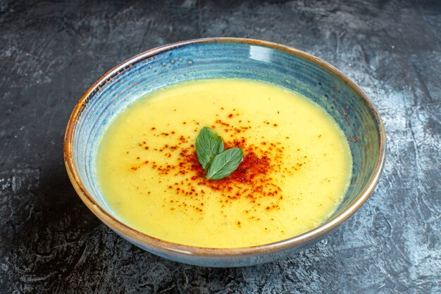 Vista anterior de una olla azul con una sabrosa sopa servida con menta en el cuadro azul