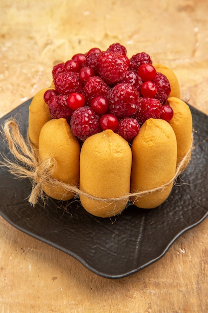 Vista anterior de un pastel de regalo con frutas en la parte central de la tabla de colores mezclados