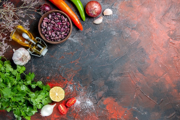 Vista anterior de la preparación de la cena con alimentos y frijoles botella de aceite caído y un manojo de tomate limón verde en la tabla de colores mezclados