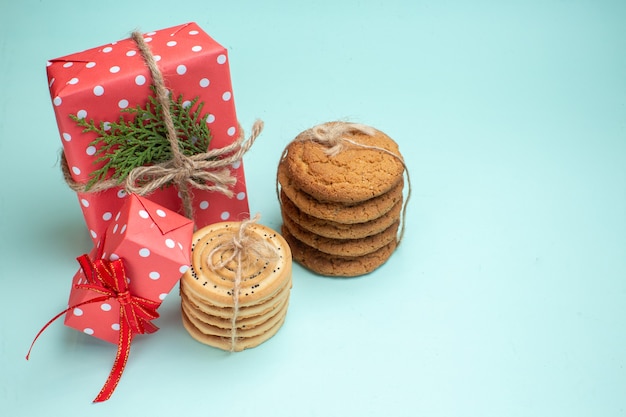 Vista anterior de varias deliciosas galletas apiladas cajas de regalo rojas sobre fondo verde pastel