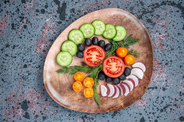 Vista anterior de verduras frescas picadas en una placa marrón en la tabla de colores mezclados