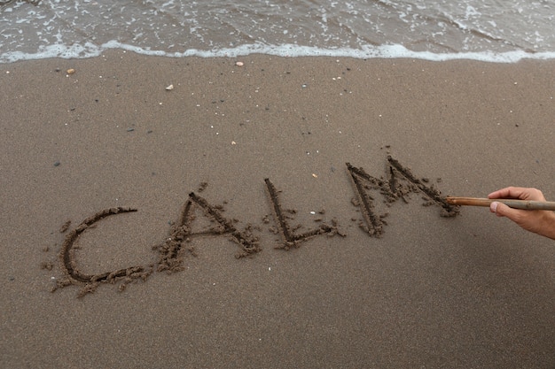Vista de la arena de la playa en verano con un mensaje escrito en ella