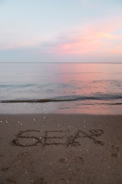 Vista de la arena de la playa en verano con un mensaje escrito en ella