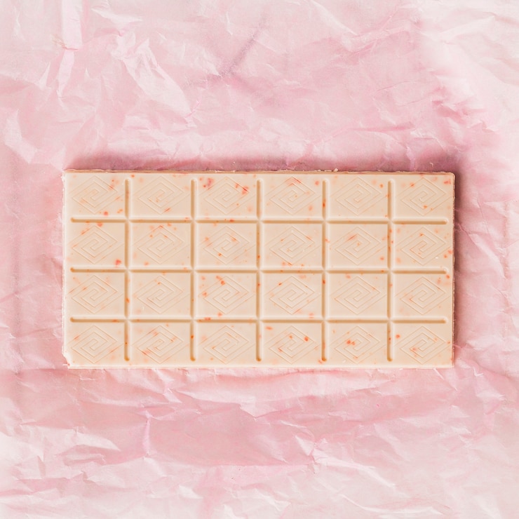 Foto gratuito una vista desde arriba de la barra de chocolate blanco en papel rosa