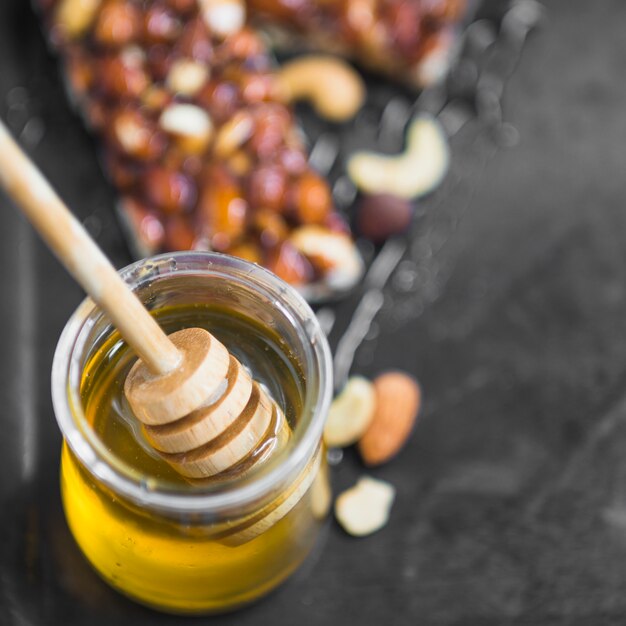 Vista de arriba del cucharón de madera en la olla de miel con sabrosas barras de granola