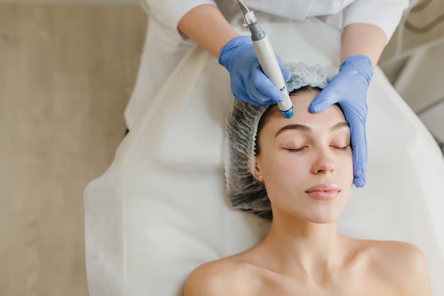 Vista desde arriba de hermosa mujer disfrutando de procedimientos de cosmetología, rejuvenecimiento en salón de belleza. Dermatología, médico en el trabajo, asistencia sanitaria, terapia, botox.