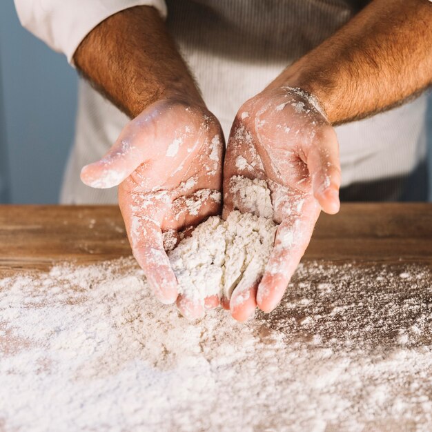 Una vista desde arriba de la mano del panadero con harina de trigo.