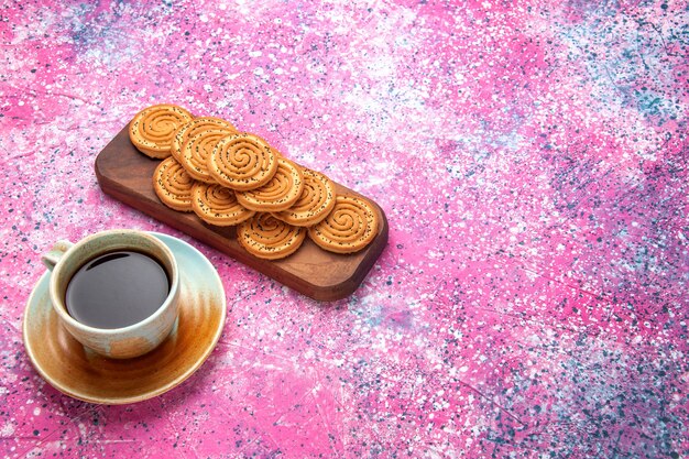 Vista desde arriba de la mitad de las galletas dulces redondas deliciosas galletitas forradas con té en el escritorio rosa.