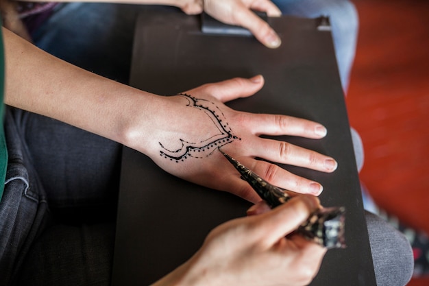 Una vista desde arriba de la mujer haciendo un tatuaje de heena de una artista femenina
