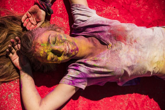 Una vista desde arriba de las mujeres jóvenes que mienten en polvo holi rojo