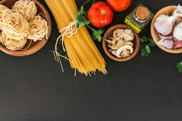 Una vista desde arriba de las pastas de tagliatelle y espaguetis con ingredientes sobre fondo negro