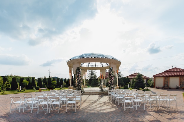 Vista de los asientos para invitados y el arco de bodas ceremoniales en la soleada plaza