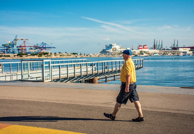 Vista brillante horizontal de un hombre mayor caminando en la orilla de una ciudad en un día soleado