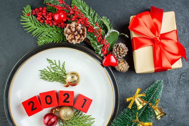 Vista de cerca de los accesorios de decoración de números en una placa ramas de abeto cono de coníferas árbol de navidad sobre fondo oscuro