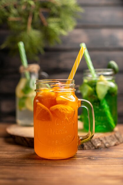 Vista de cerca de agua de desintoxicación y jugo fresco en botellas con tubos sobre fondo de madera marrón