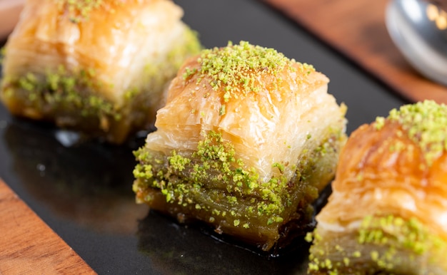 Vista de cerca de baklava turco tradicional con pistacho en un tablero negro