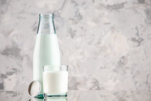 Vista de cerca de la botella de vidrio y la taza llena con tapón de leche sobre fondo de colores pastel con espacio libre