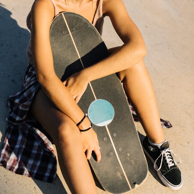 Vista de cerca de chica skater sujetando su tabla