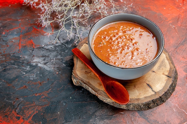 Vista de cerca de la clásica sopa de tomate en un tazón azul cuchara en bandeja de madera en la mesa de colores mezclados