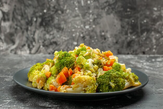 Vista de cerca de comida saludable con brocoli y zanahorias en una placa negra con tenedor y cuchillo