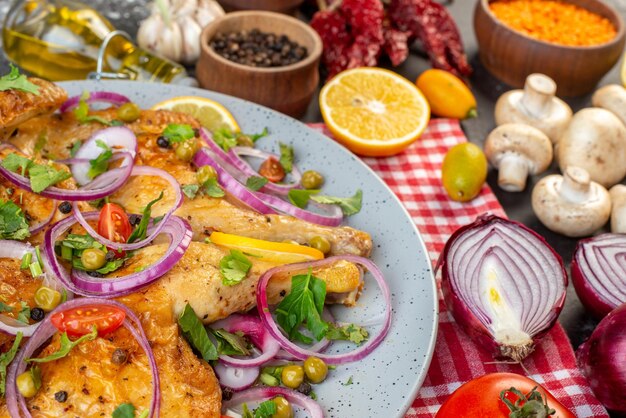 Vista de cerca de una deliciosa cena plato de pollo frito con varias especias y alimentos ajos botella de aceite caído cebollas de limón champiñones kumquats