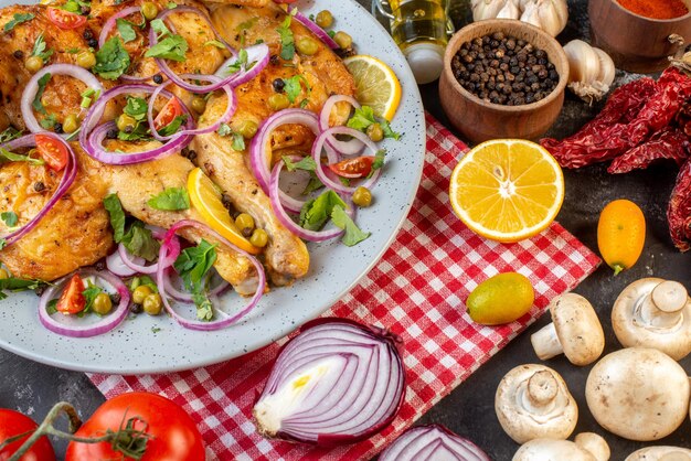 Vista de cerca de una deliciosa cena plato de pollo frito con varias especias y alimentos ajos botella de aceite caído limón pimientos secos champiñones kumquats