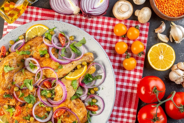 Vista de cerca de una deliciosa cena plato de pollo frito con varias especias y alimentos tomates con tallos ajos de lentejas rojas botella de aceite caída champiñones de limón sobre fondo de color oscuro