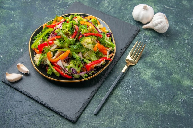 Vista de cerca de una deliciosa ensalada de verduras con varios ingredientes en la tabla de cortar negra