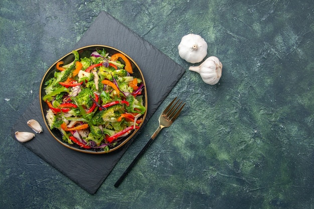 Vista de cerca de una deliciosa ensalada de verduras con varios ingredientes en la tabla de cortar negra