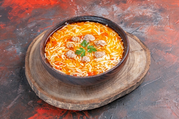 Vista de cerca de la deliciosa sopa de fideos con pollo en la tabla de cortar de madera sobre fondo oscuro