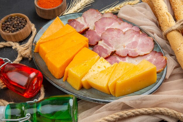 Vista de cerca de deliciosos bocadillos botellas caídas pimientos en toalla y cuerda sobre un fondo negro